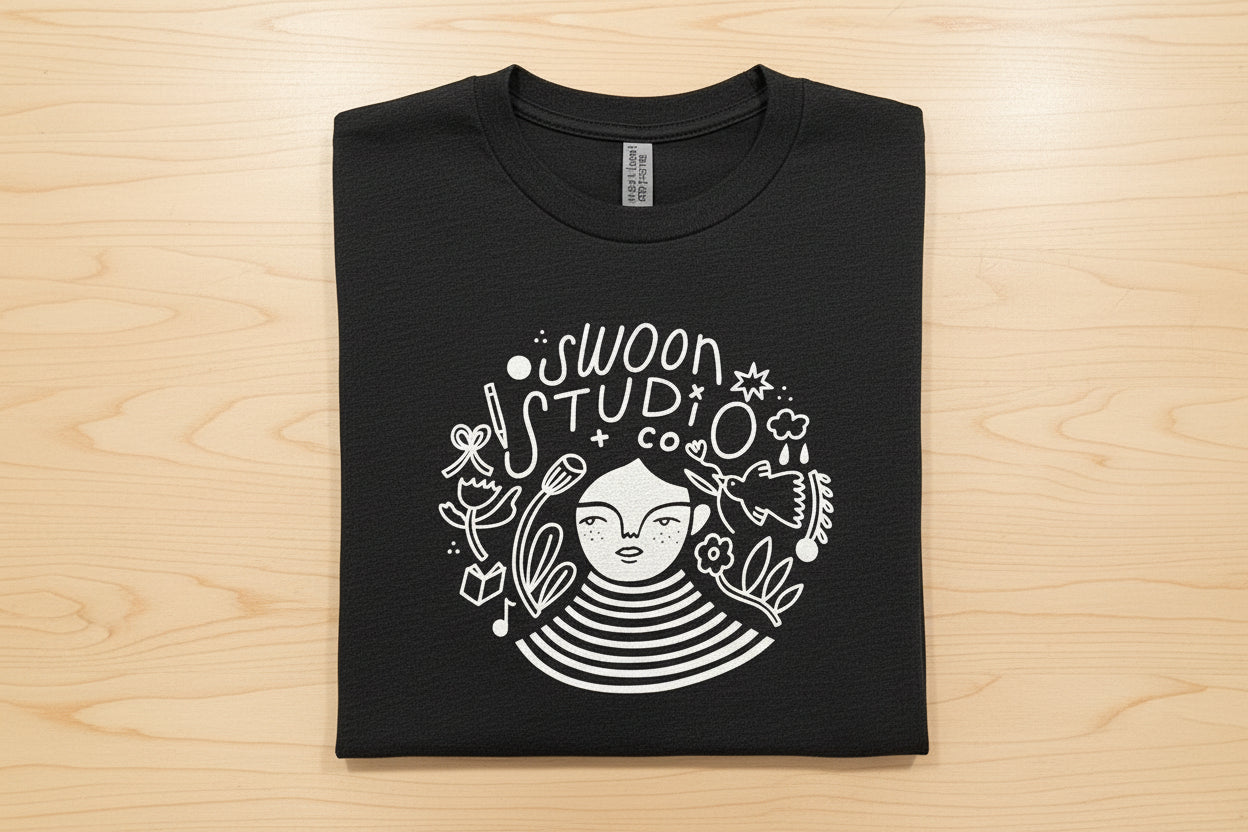 Black t-shirt with white graphic design on a wooden surface